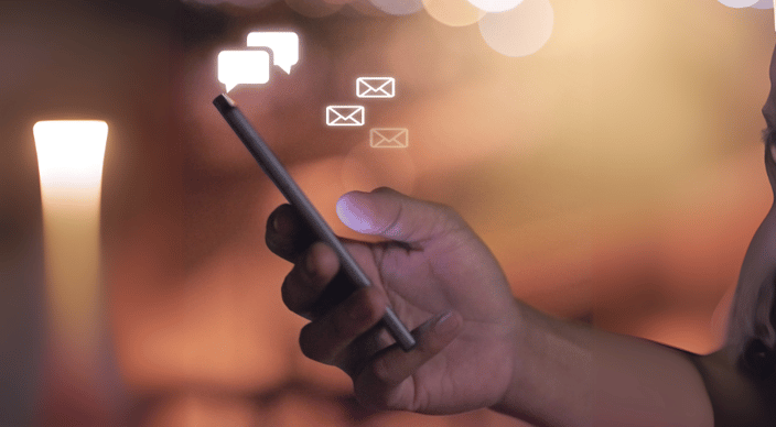 Hand holding a smartphone with floating message and email icons.